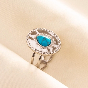 Close-up of adjustable stainless steel ring with turquoise stone on beige fabric