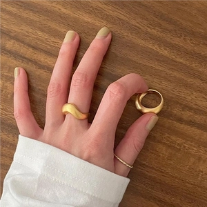 Detailed view of minimalist matte gold twist rings and sleek wave design on finger
