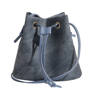 Minimalist blue denim drawstring bucket bag with brass rings and adjustable strap