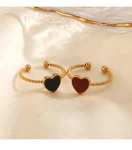 Detail of gold open rings with heart shaped black and red enamel on white silk fabric