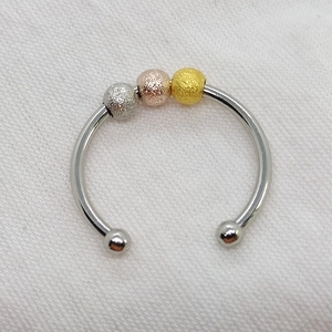 Macro view of tri-color frosted spinning beads on a polished stainless steel open ring