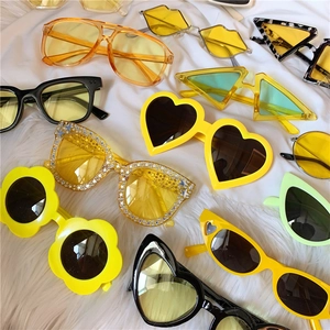 Colorful retro daisy and heart shaped sunglasses collection on a white plush background