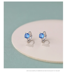 Close-up of S925 silver hoop earrings with four-prong set blue round zircon stones