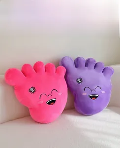 Detail showing pink and purple plush foot pillows with cartoon smiles on a soft sofa