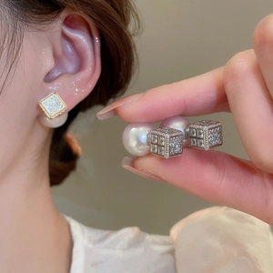 Detail of elegant square zircon stud earring with pearl backing worn on earlobe