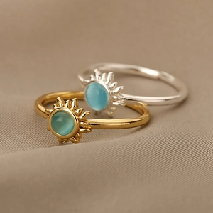 Detail view of gold and silver sun rings featuring round turquoise opal center stones