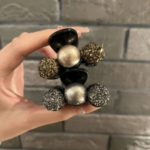 Close-up of hair clips featuring central pearl beads and shimmering rhinestone spheres