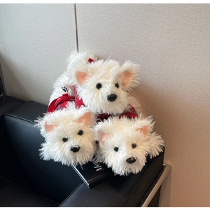 Detailed view of three Westie plush toys in red plaid outfits on a dark sofa