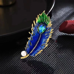 Detailed view of peacock feather brooch with blue zircon, green enamel and white pearl