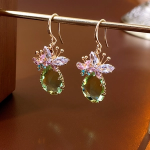 Détail macro de la boucle d'oreille goutte émeraude avec zircons papillons colorés