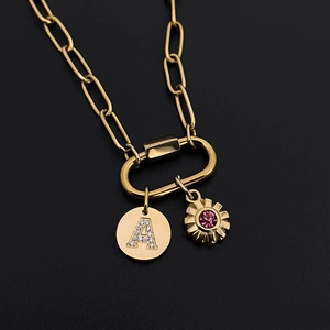 Close-up of gold paperclip chain necklace with sparkling letter A and pink flower charms.