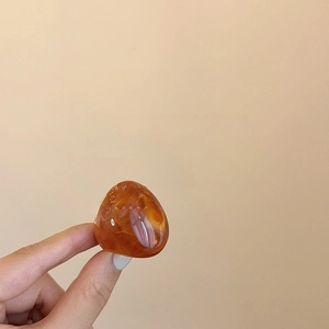Detail shot of the polished amber orange resin gemstone set on a gold plated ring