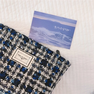 Detail of tweed makeup bag showing blue and white weave with a 'TIME TO PARTY' label