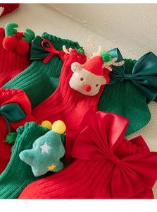 Close-up of knit Christmas socks with 3D reindeer, tree icons and bow decorations
