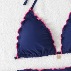 Detail view of navy bikini top with pink scalloped trim and gold sunburst pendant