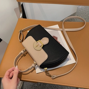 Detail of two-tone crossbody bag with lychee texture leather and gold horseshoe buckle