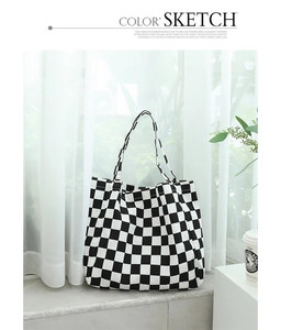 Detail of black and white checkered canvas tote bag by a window with soft lighting