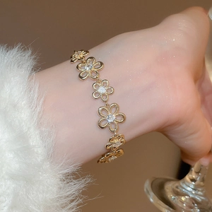 Detailed close-up of golden hollow flower bracelet with sparkling zircons on model wrist
