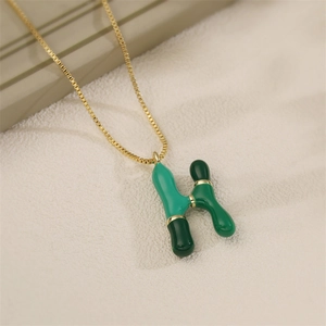 Collana a catena dorata con ciondolo lettera H in smalto verde su base beige