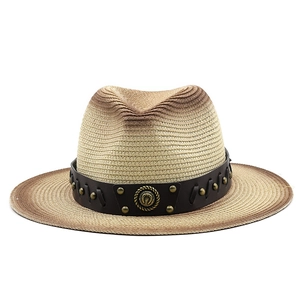 Detail of gradient straw fedora hat featuring a brown leather band and metallic horseshoe emblem