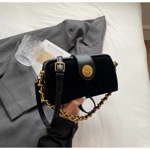 Detail of vintage black suede doctor bag featuring a gold embossed clasp and chain handle