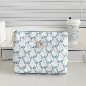 Detail of quilted white makeup bag with light blue bows and good night label