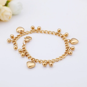 Detail of gold stainless steel bracelet with heart charms and beads on white background