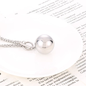 Macro view of silver ball pendant necklace with OT toggle clasp on a white plate