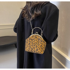 Leopard print shell bag with golden chain strap worn by model against a white wall