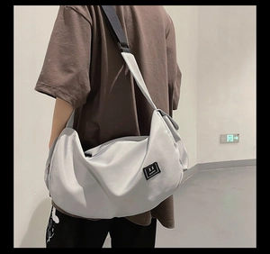 Detailed view of gray large capacity messenger bag with adjustable black strap and patch
