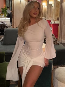 Détail de mini robe blanche asymétrique avec manches évasées et nœud drapé décoratif