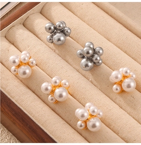 Detail of cluster pearl earrings in gold and silver finishes on a beige jewelry display
