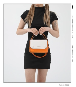 Detail of orange and white contrast crossbody bag with JINGPINPIJU lettering and top handle