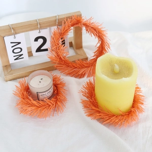 Close-up of three orange tinsel candle rings on linen with rustic autumn decor