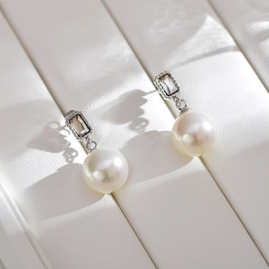 Macro shot of elegant pearl drop earrings with rectangular crystal and silver frame
