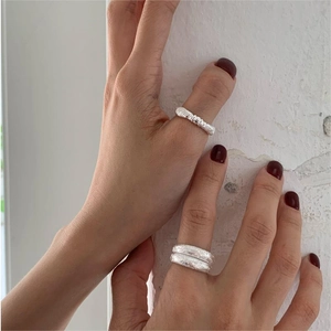 Detailed view of 925 sterling silver knotted and textured rings worn on a model hand