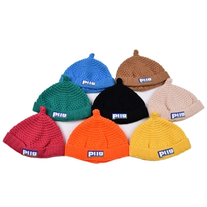 Flat lay of colorful knitted baby beanies in eight vibrant shades with PIIg fabric tags