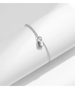 Macro shot of silver padlock charm bracelet displayed on a white cylindrical stand