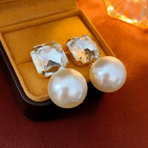 Macro detail of elegant square crystal and pearl drop earring in a yellow velvet box