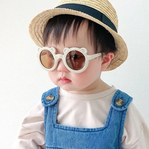 Dettaglio di un modello baby con occhiali da sole a forma di orso color crema