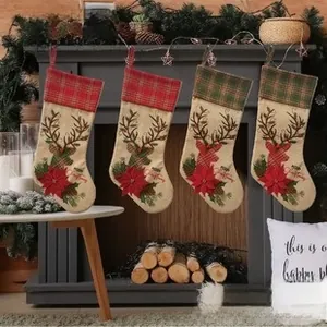 Detail of four rustic burlap Christmas stockings with reindeer and poinsettia hanging on a mantel