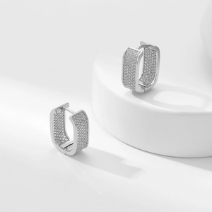 Makroaufnahme von U-förmigen Silber-Ohrringen mit Zirkonia-Mikropflaster auf weißem Sockel