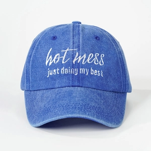 Detail of blue washed denim baseball cap with hot mess white embroidery texture