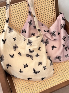 Chic tote bags with black butterfly prints in beige and pink on a wooden chair