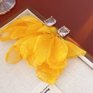 Detailansicht der gelben Stoffblumen-Ohrringe mit quadratischem Kristall auf Leinen