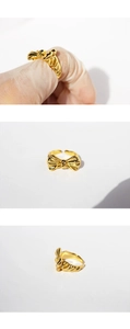 Detailed views of a gold-plated brass 3D bow ring showing fit and close-up metal texture