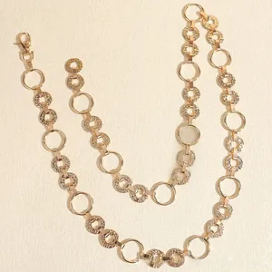 Detail of gold chain belt featuring alternating smooth and hammered texture metal discs