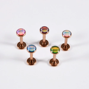 Detail of five rose gold labret studs with multi-color iridescent gradient gemstones