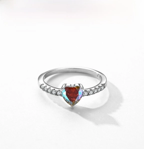 Macro view of heart-shaped orange gemstone ring with silver band and side stones