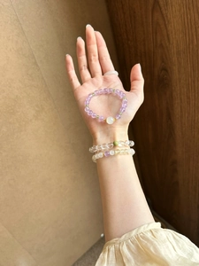 Detailed close-up of natural amethyst and white crystal beaded bracelets on wrist